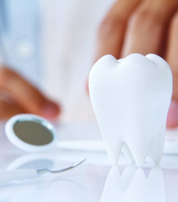 Model of a tooth next to a dental mirror