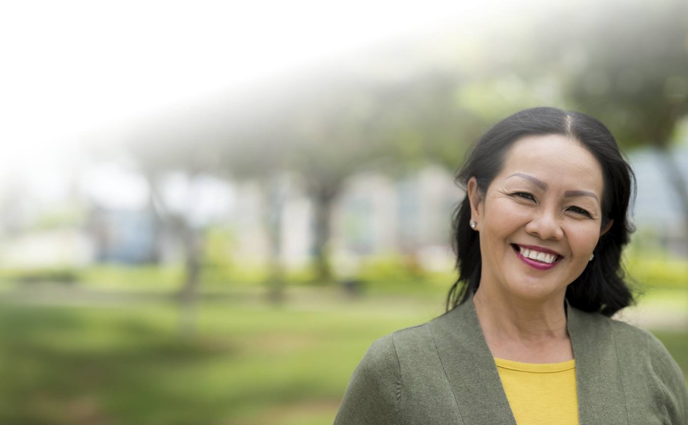 Woman in olive green jacket smiling with dental implants in Julington Creek