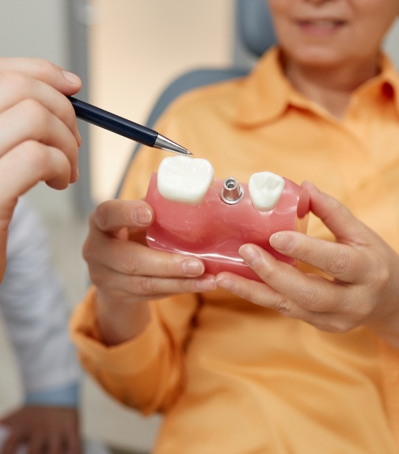 Dentist showing a patient a dental implant model