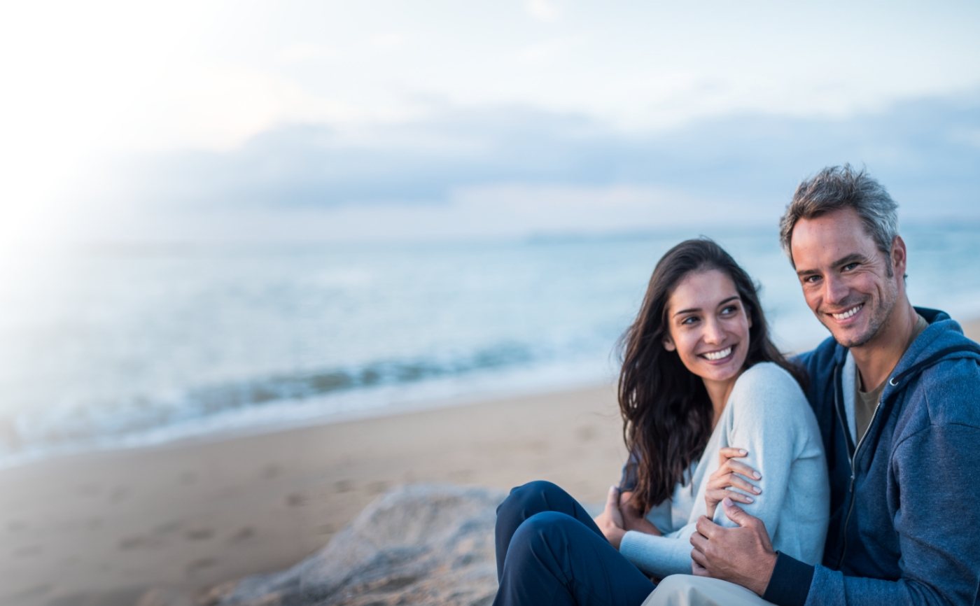 Smiling man and woman on beach after receiving dental services in Julington Creek