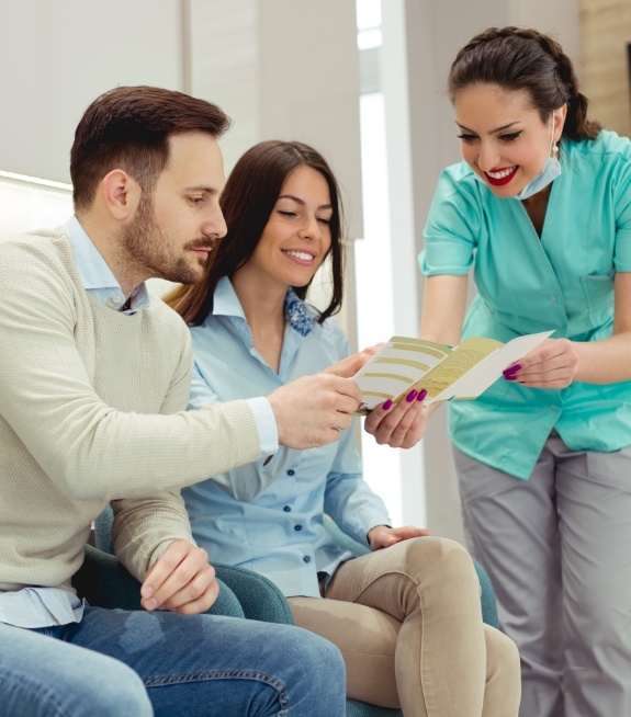 Dental team member showing a pamphlet to two patients