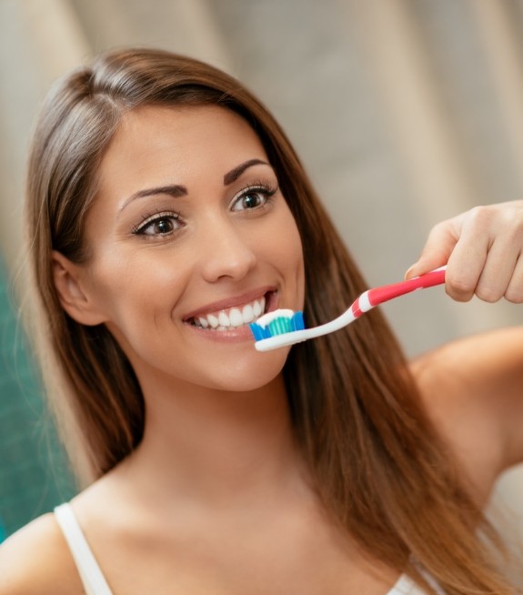 Woman smiling while brushing her teeth