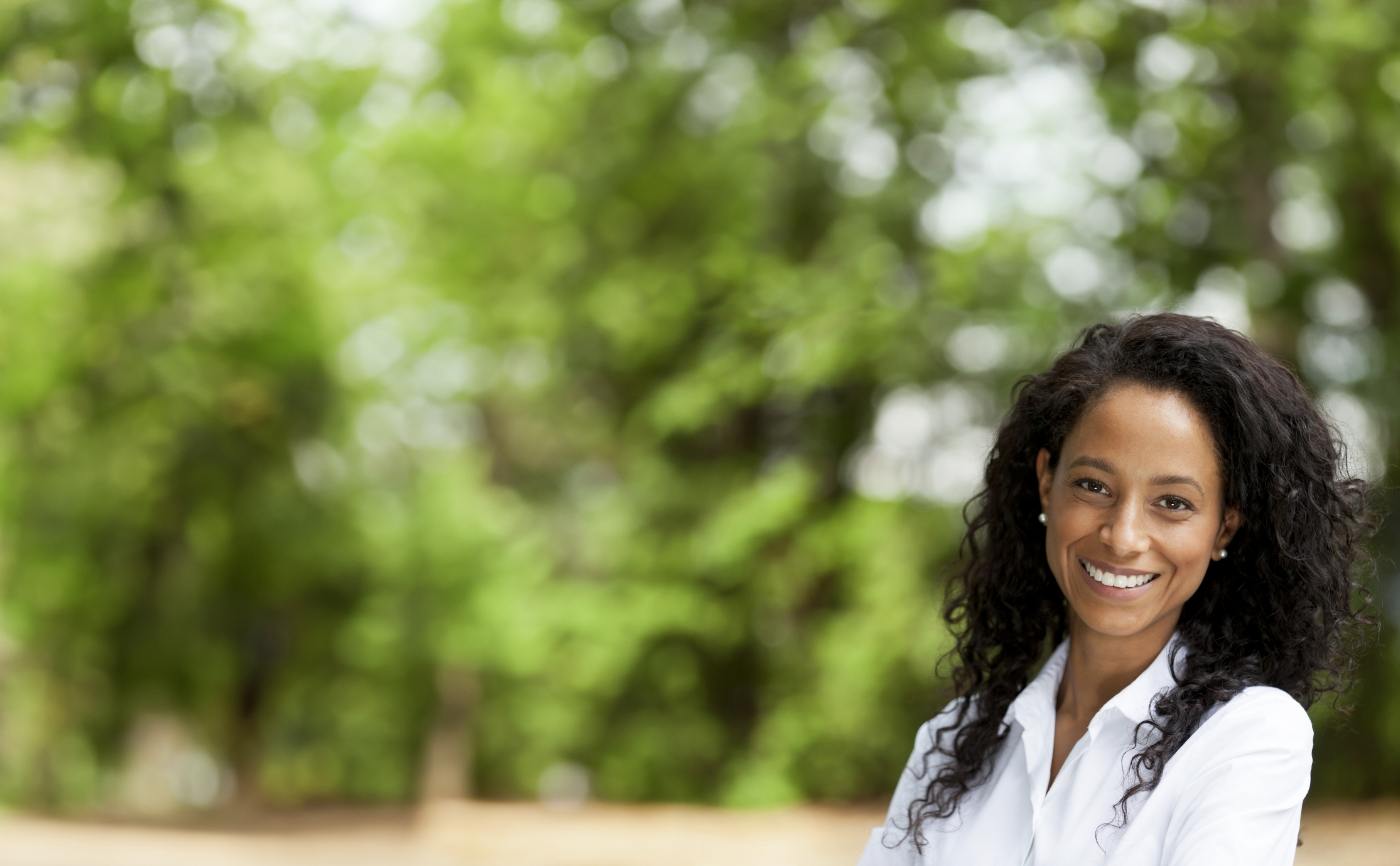 Woman in white collared shirt smiling outdoors