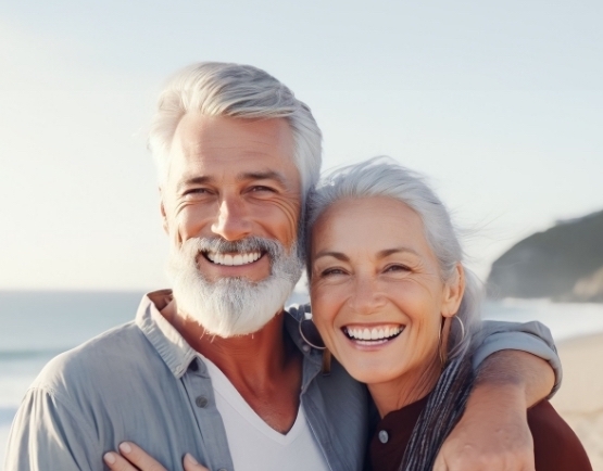 Senior man and woman smiling on beach after visiting dentist in Julington Creek