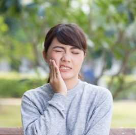 Woman wincing and holding her cheek in pain