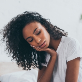 Woman in white tee shirt holding her jaw in pain