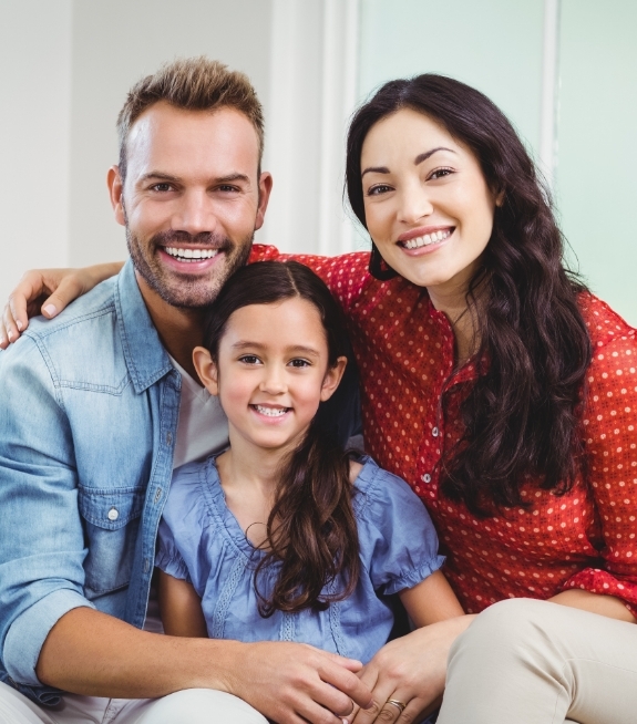 Smiling family of three sitting on couch