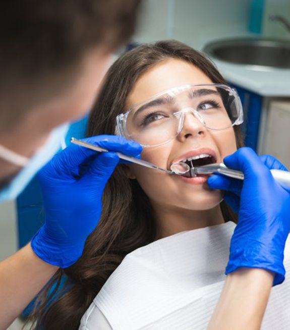 Young woman sitting in patient’s chair while dentist works