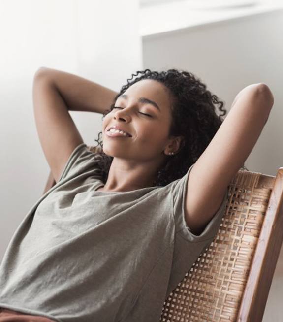 Woman leaning back and relaxing in whicker-backed chair