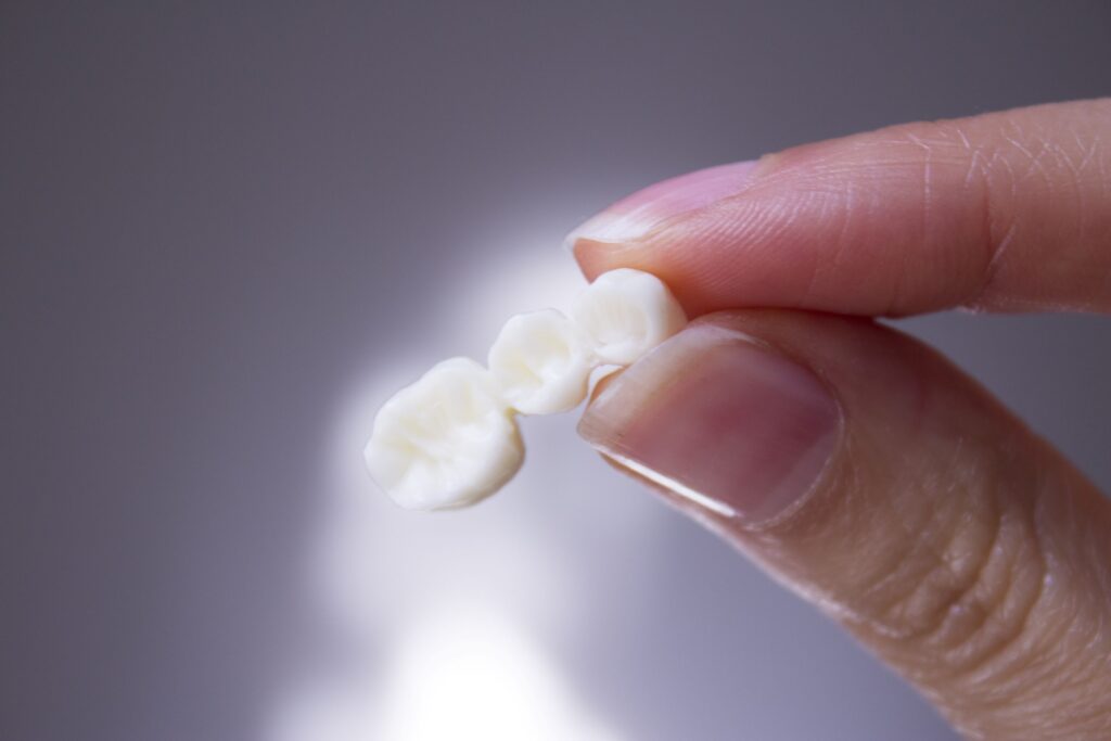 Closeup of fingers holding a dental bridge